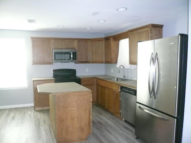 502 Ross St, Smithville, TX 78957 - kitchen with stainless steel appliances, a center island, light wood-type flooring, tile counters, and brown cabinets