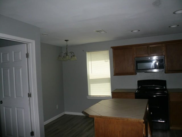 502 Ross St, Smithville, TX 78957 - kitchen with stainless steel microwave, black electric range, tile countertops, a chandelier, and dark wood-style flooring