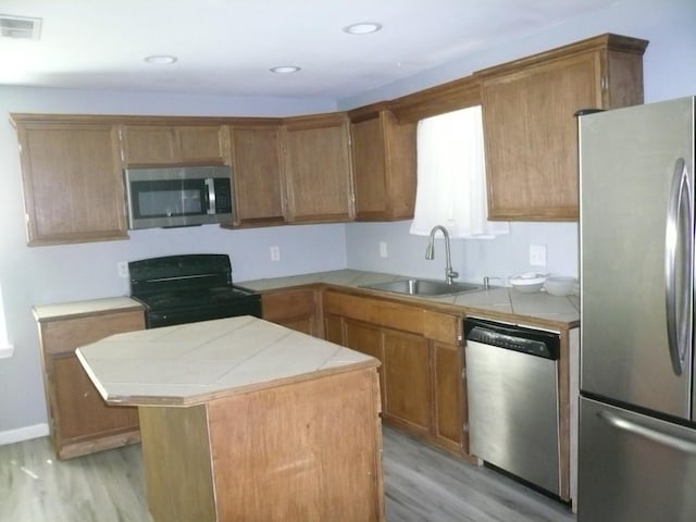 502 Ross St, Smithville, TX 78957 - kitchen featuring stainless steel appliances, light wood finished floors, tile countertops, brown cabinetry, and recessed lighting