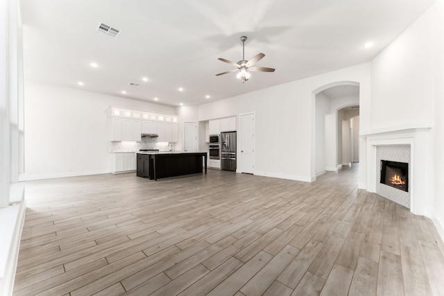 2935 Mckinnie Park, Bulverde, TX 78163 - unfurnished living room featuring a ceiling fan, light wood-style flooring, a glass covered fireplace, recessed lighting, and arched walkways