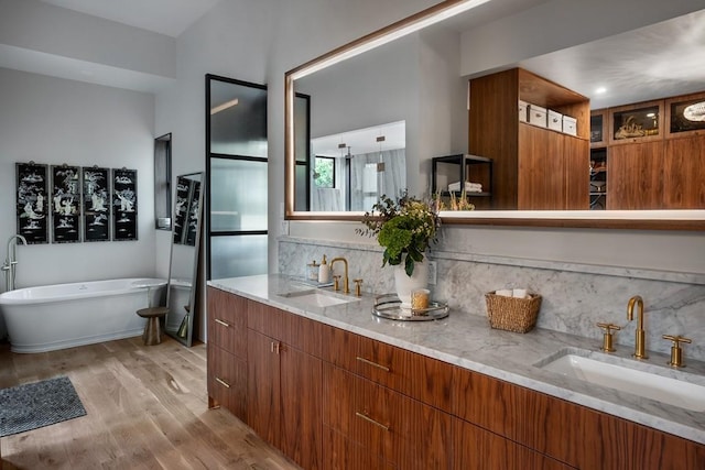 1001 Madrone Rd, West Lake Hills, TX 78746 - bathroom featuring wood finished floors, double vanity, a soaking tub, and backsplash