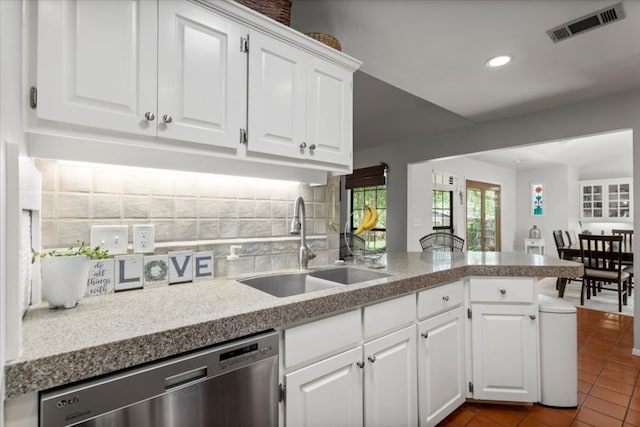 225 Spanish Oak Dr, Georgetown, TX 78628 - kitchen with stainless steel dishwasher, a peninsula, tasteful backsplash, white cabinets, and dark tile patterned floors