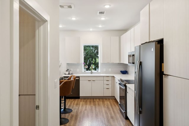 4802 S Congress Ave Unit 215, Austin, TX 78745 - kitchen featuring stainless steel appliances, light countertops, backsplash, light wood finished floors, and modern cabinets