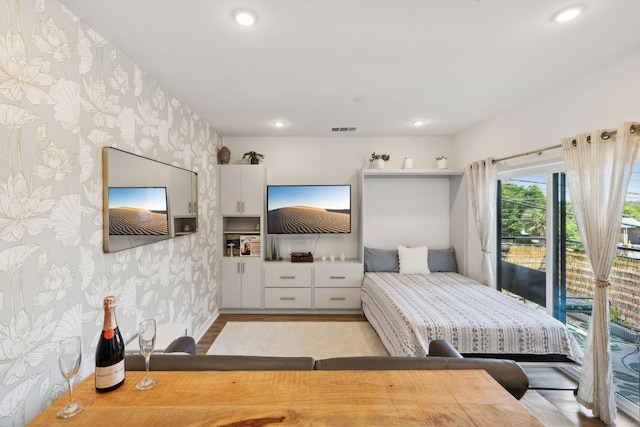 4802 S Congress Ave Unit 215, Austin, TX 78745 - bedroom with wallpapered walls, wood finished floors, recessed lighting, and access to exterior