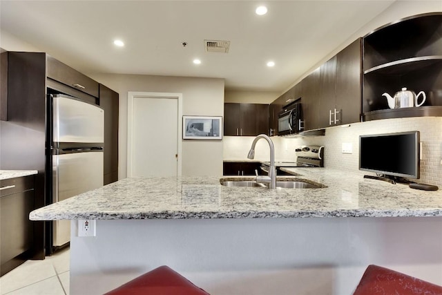 40 N Interstate 35 Hwy Unit 5B2, Austin, TX 78701 - kitchen featuring black microwave, freestanding refrigerator, light stone countertops, decorative backsplash, and a peninsula