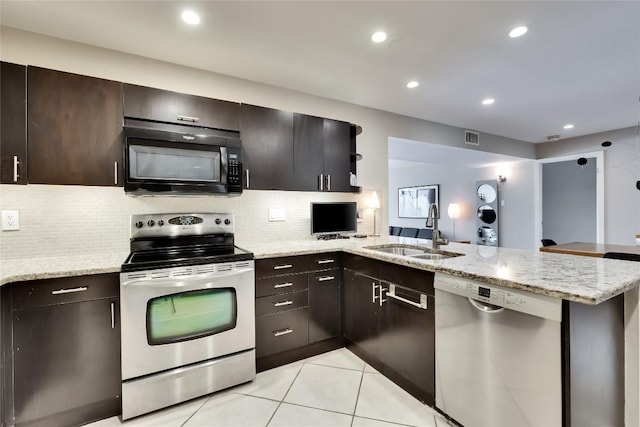 40 N Interstate 35 Hwy Unit 5B2, Austin, TX 78701 - kitchen featuring stainless steel appliances, a peninsula, backsplash, light tile patterned flooring, and light stone counters