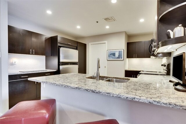40 N Interstate 35 Hwy Unit 5B2, Austin, TX 78701 - kitchen with a peninsula, light stone countertops, decorative backsplash, dark brown cabinetry, and recessed lighting