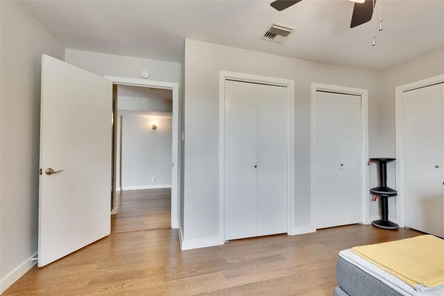 40 N Interstate 35 Hwy Unit 5B2, Austin, TX 78701 - unfurnished bedroom featuring two closets, light wood-style flooring, and a ceiling fan