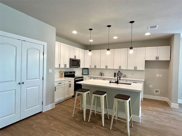 102 Halawa Ct, Bastrop, TX 78602 - kitchen with electric range oven, stainless steel microwave, white cabinetry, wood finished floors, and recessed lighting