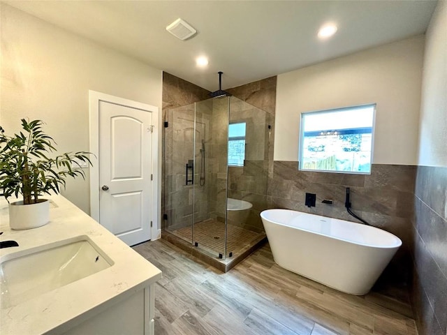 102 Halawa Ct, Bastrop, TX 78602 - full bath with a shower stall, a soaking tub, tile walls, double vanity, and wood finished floors
