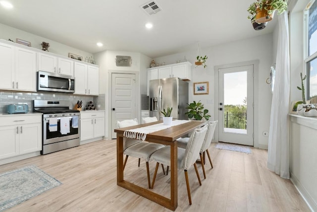 7713 Saddle Up Dr, Austin, TX 78724 - kitchen with stainless steel appliances, backsplash, light wood-style flooring, white cabinetry, and recessed lighting