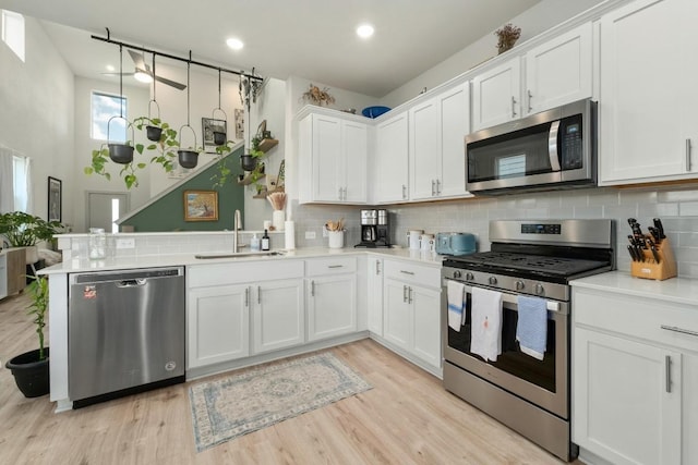 7713 Saddle Up Dr, Austin, TX 78724 - kitchen with appliances with stainless steel finishes, backsplash, white cabinets, a peninsula, and recessed lighting