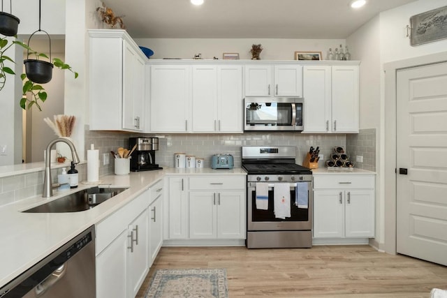 7713 Saddle Up Dr, Austin, TX 78724 - kitchen with appliances with stainless steel finishes, white cabinetry, light countertops, light wood-style floors, and recessed lighting