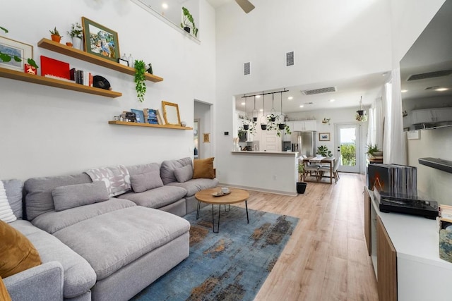 7713 Saddle Up Dr, Austin, TX 78724 - living room featuring light wood finished floors, a towering ceiling, and ceiling fan