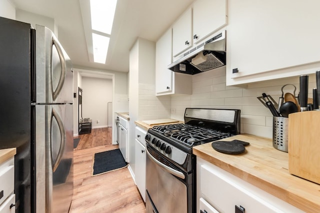 1212 Guadalupe St Unit 301, Austin, TX 78701 - kitchen with stainless steel appliances, under cabinet range hood, white cabinetry, butcher block countertops, and tasteful backsplash
