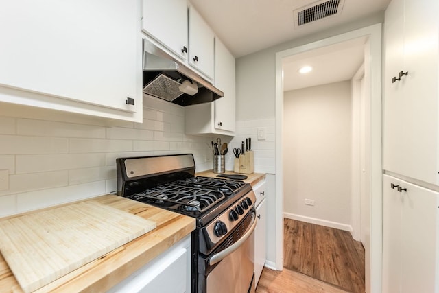 1212 Guadalupe St Unit 301, Austin, TX 78701 - kitchen featuring stainless steel gas range, under cabinet range hood, light wood-style floors, butcher block counters, and white cabinets