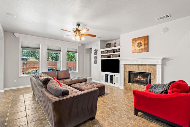 1600 Grand Falls Dr, Cedar Park, TX 78613 - living area with built in features, a ceiling fan, a tiled fireplace, and a textured ceiling