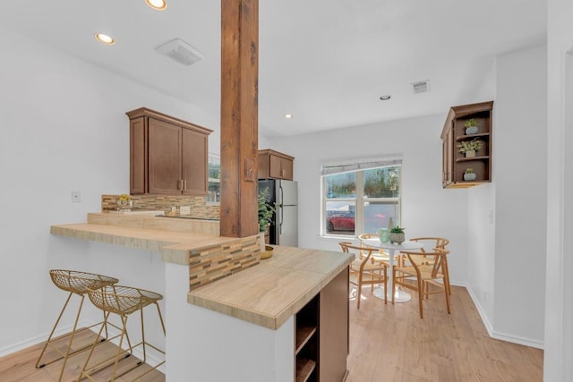 2414 Longview St Unit 101, Austin, TX 78705 - kitchen with freestanding refrigerator, open shelves, tasteful backsplash, recessed lighting, and a kitchen bar