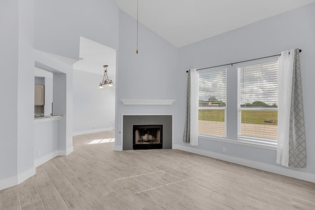 131 Martin Crossing Dr, Cedar Creek, TX 78612 - unfurnished living room featuring light wood-style floors, a tile fireplace, a towering ceiling, and a chandelier