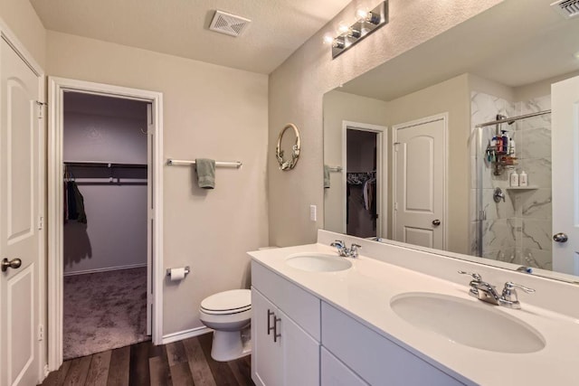 501 Goat Willow Ln, Georgetown, TX 78626 - bathroom featuring double vanity, a walk in closet, a stall shower, and wood finished floors
