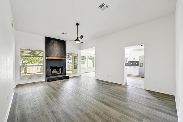 1105 Madrone Trl, Leander, TX 78641 - unfurnished living room with ceiling fan, a brick fireplace, and wood finished floors