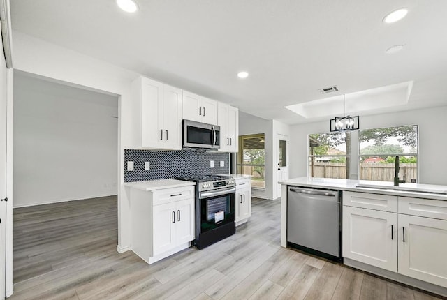 1105 Madrone Trl, Leander, TX 78641 - kitchen featuring stainless steel appliances, light countertops, recessed lighting, light wood-type flooring, and white cabinetry