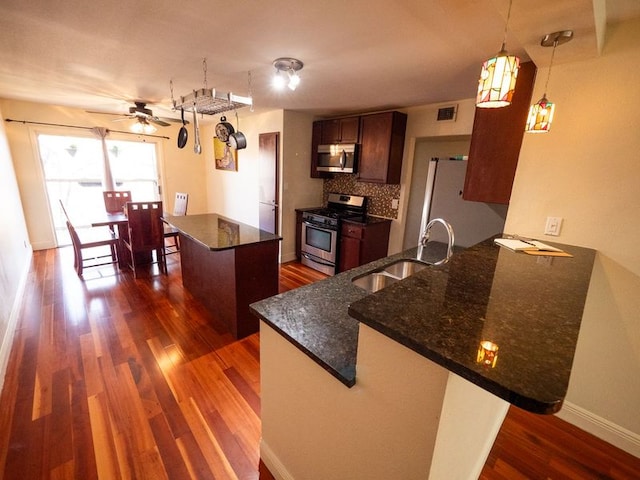 2303 Eastside Dr # 209, Austin, TX 78704 - kitchen with stainless steel appliances, dark wood-style floors, a peninsula, a ceiling fan, and dark stone counters