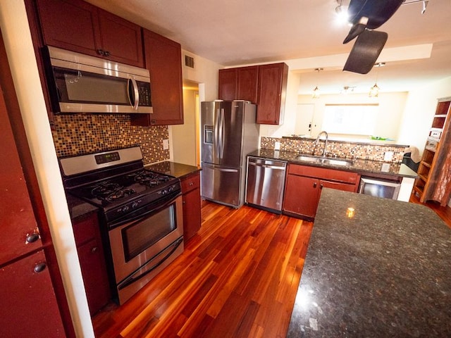 2303 Eastside Dr # 209, Austin, TX 78704 - kitchen featuring appliances with stainless steel finishes, decorative backsplash, dark wood-style floors, and dark stone counters