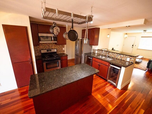 2303 Eastside Dr # 209, Austin, TX 78704 - kitchen featuring appliances with stainless steel finishes, wine cooler, a peninsula, dark wood-style floors, and decorative backsplash