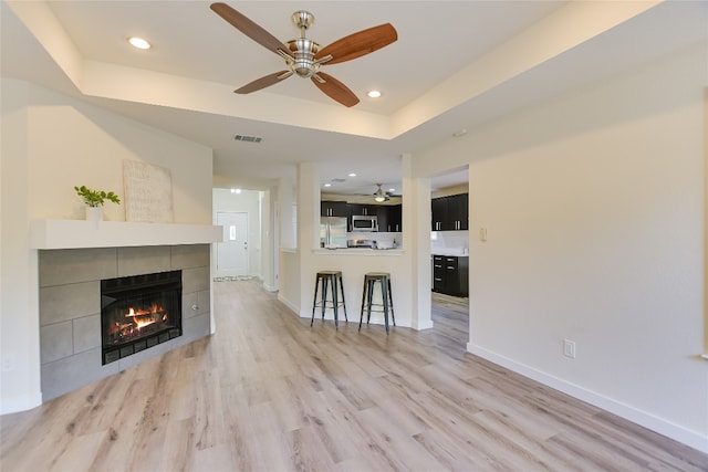5509 Kayview Dr, Austin, TX 78749 - living room with ceiling fan, a tiled fireplace, light wood-style flooring, recessed lighting, and a raised ceiling