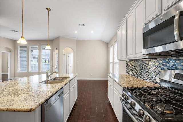 17900 Crimson Apple Way, Pflugerville, TX 78660 - kitchen featuring appliances with stainless steel finishes, arched walkways, white cabinetry, dark wood-style floors, and tasteful backsplash