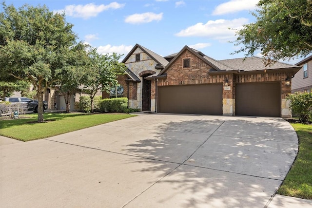 17900 Crimson Apple Way, Pflugerville, TX 78660 - view of front of property featuring stone siding, concrete driveway, an attached garage, a front lawn, and brick siding