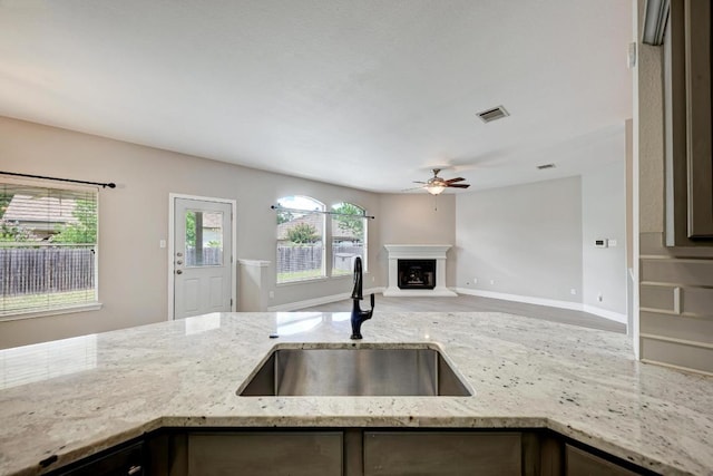4408 Tello Path, Austin, TX 78749 - kitchen with ceiling fan, open floor plan, light stone counters, a fireplace with raised hearth, and wood finished floors