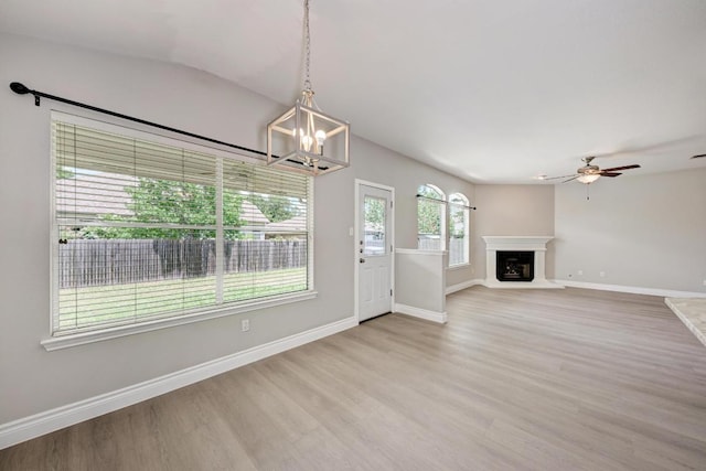 4408 Tello Path, Austin, TX 78749 - unfurnished living room featuring light wood finished floors, a ceiling fan, a fireplace with raised hearth, a chandelier, and vaulted ceiling