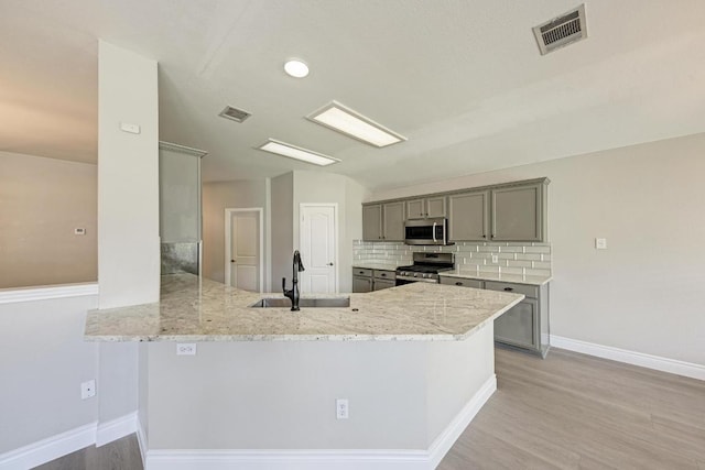 4408 Tello Path, Austin, TX 78749 - kitchen with appliances with stainless steel finishes, gray cabinets, backsplash, and a peninsula