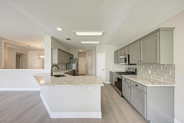 4408 Tello Path, Austin, TX 78749 - kitchen with appliances with stainless steel finishes, a peninsula, light wood-style flooring, light stone counters, and recessed lighting