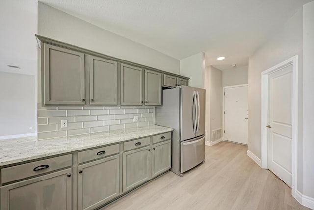 4408 Tello Path, Austin, TX 78749 - kitchen featuring freestanding refrigerator, decorative backsplash, light wood-style flooring, light stone counters, and gray cabinets