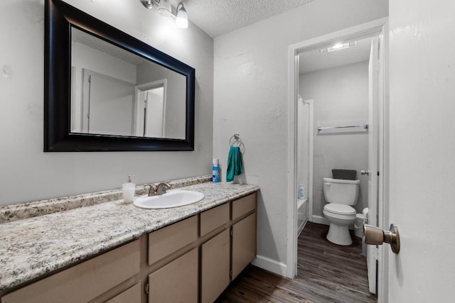 10706 Topperwein Dr, Austin, TX 78758 - bathroom with wood finished floors, vanity, a textured ceiling, and  shower combination