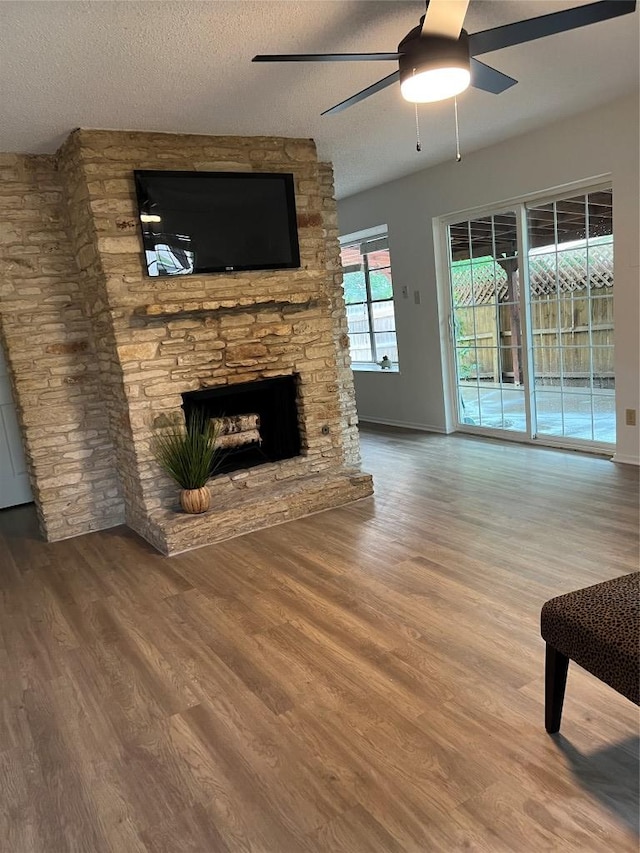 6506 Clubway Ln, Austin, TX 78745 - unfurnished living room with ceiling fan, wood finished floors, a stone fireplace, and a textured ceiling