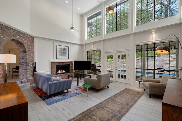 5301 Backtrail Dr, Austin, TX 78731 - living area with a towering ceiling, a decorative wall, a brick fireplace, a ceiling fan, and french doors