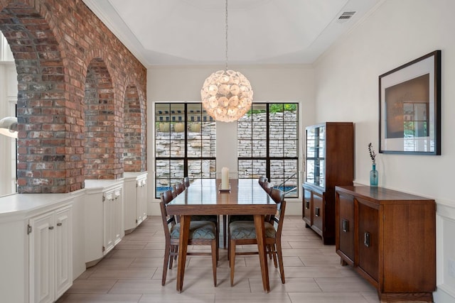 5301 Backtrail Dr, Austin, TX 78731 - dining area featuring brick wall, a chandelier, ornamental molding, and arched walkways