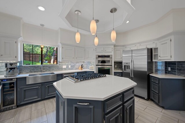 5301 Backtrail Dr, Austin, TX 78731 - kitchen featuring appliances with stainless steel finishes, beverage cooler, white cabinetry, light countertops, and a kitchen island