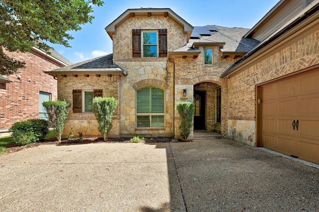 3340 Marcasite Dr, Round Rock, TX 78681 - french country home with stone siding, roof with shingles, solar panels, an attached garage, and brick siding