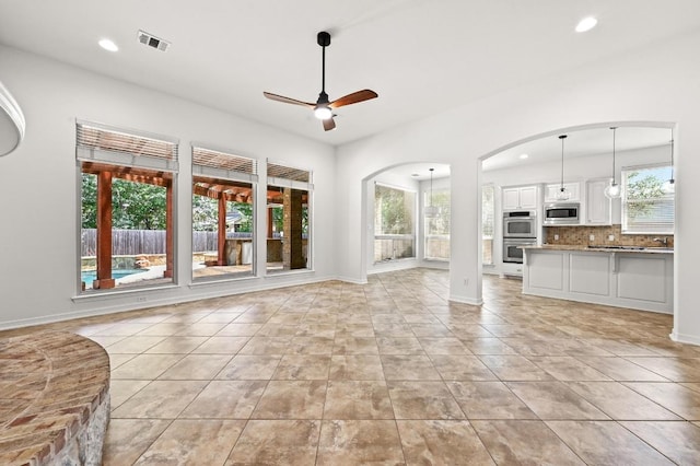 3340 Marcasite Dr, Round Rock, TX 78681 - unfurnished living room with ceiling fan, plenty of natural light, arched walkways, recessed lighting, and light tile patterned floors