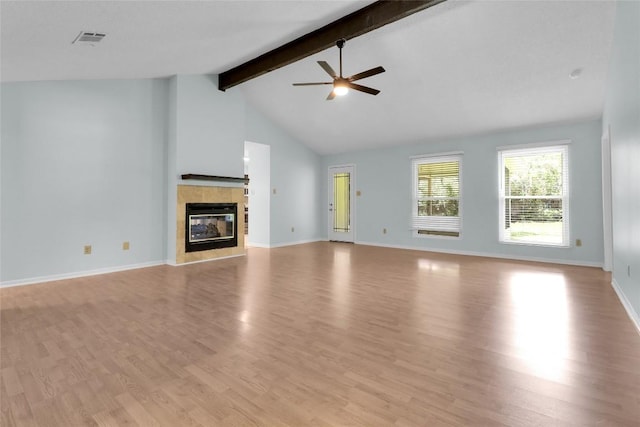 1928 Ramona Cir, San Marcos, TX 78666 - unfurnished living room with a ceiling fan, beamed ceiling, light wood-style floors, a tile fireplace, and high vaulted ceiling