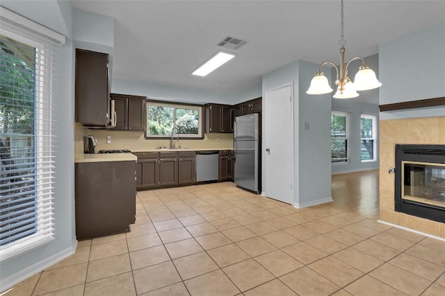 1928 Ramona Cir, San Marcos, TX 78666 - kitchen with stainless steel appliances, light countertops, dark brown cabinets, light tile patterned flooring, and a chandelier