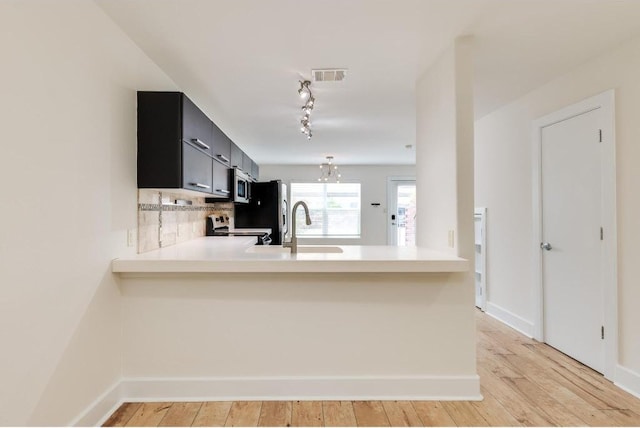 1101 Grove Blvd Unit 102, Austin, TX 78741 - kitchen with stainless steel appliances, light countertops, a peninsula, dark cabinetry, and rail lighting