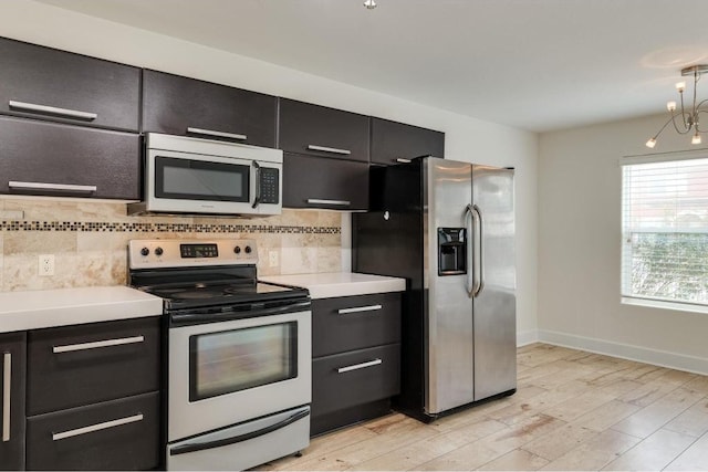 1101 Grove Blvd Unit 102, Austin, TX 78741 - kitchen with appliances with stainless steel finishes, dark cabinetry, light countertops, decorative backsplash, and light wood-style flooring