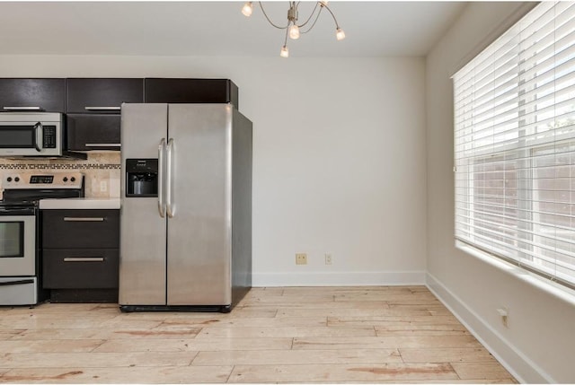1101 Grove Blvd Unit 102, Austin, TX 78741 - kitchen with appliances with stainless steel finishes, dark cabinets, light wood-style floors, a chandelier, and light countertops