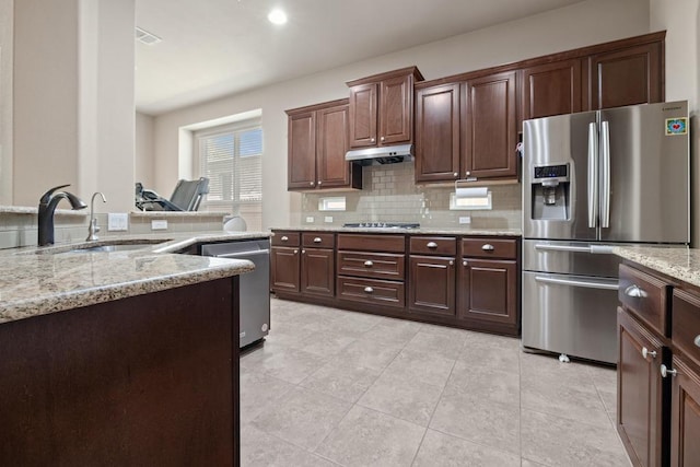 614 Spanish Mustang Dr, Cedar Park, TX 78613 - kitchen featuring appliances with stainless steel finishes, under cabinet range hood, backsplash, light stone counters, and light tile patterned floors